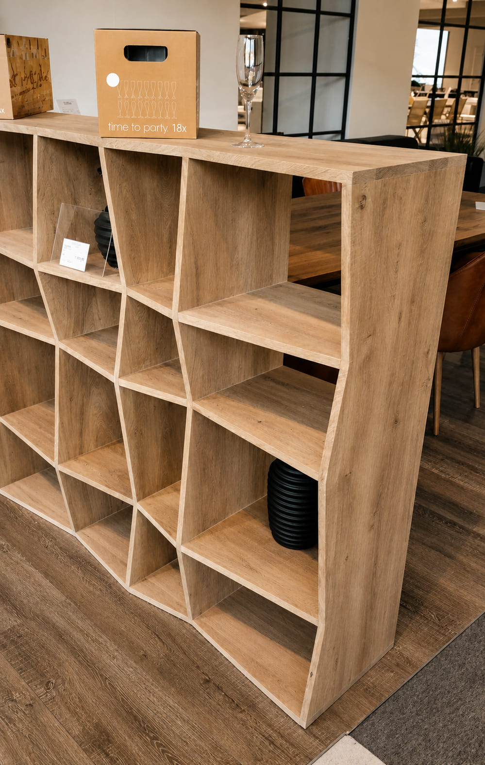 Freestanding oak shelving unit with angled, diamond-shaped compartments in a showroom