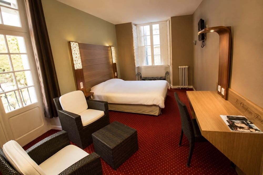 Hotel guest room with a walnut headboard and a matching desk with an integrated luggage bench