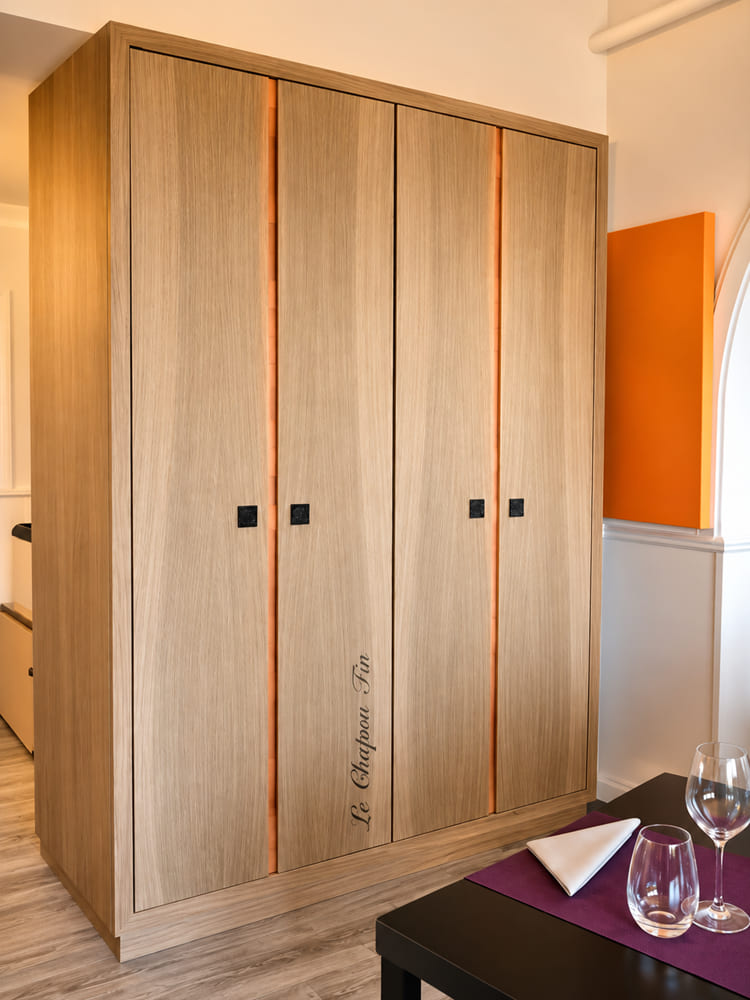 Full-height oak fitted wardrobe with orange reveal accents and an engraved name on the door