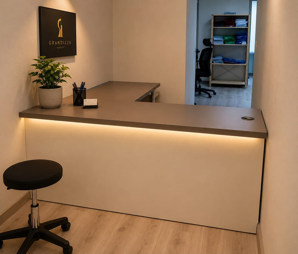 Compact L-shaped reception desk with a grey top and warm LED under-lighting